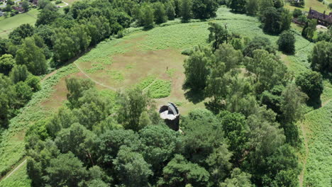 An-aerial-shot-circuling-an-old-folly-tower-in-the-English-countryside,-keeping-the-folly-in-shot