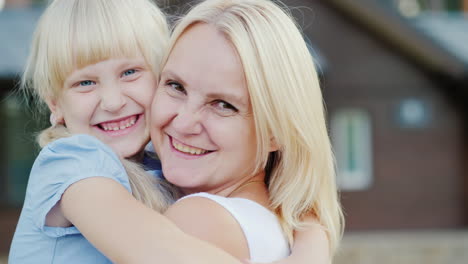 retrato de una madre con una hija pequeña abrazándose contra el fondo de su nuevo hogar mirando