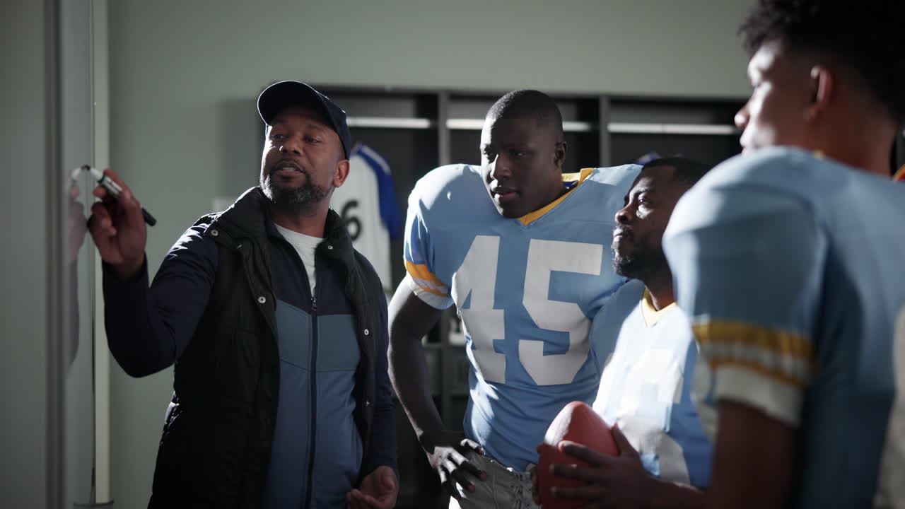 Football coach strategizing with his team in the locker room