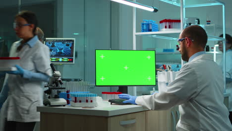 scientist man typing on computer with green mockup