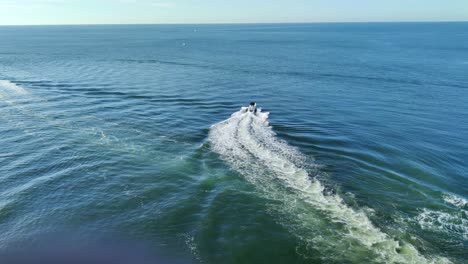 Una-Lancha-Rápida-Moviéndose-Rápido-En-Medio-Del-Mar-Con-Un-Hermoso-Sendero-En-El-Agua-Disparado-Por-Un-Dron-|-Vista-Aérea-De-Una-Lancha-Rápida-Moviéndose-En-Medio-Del-Fondo-De-Video-Del-Mar-En-4k