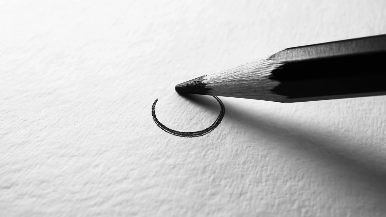Primo piano di una punta di matita affilata che tocca carta bianca testurizzata, lasciando una sottile linea di grafite curva su una superficie minimalista con un'ombra morbida.