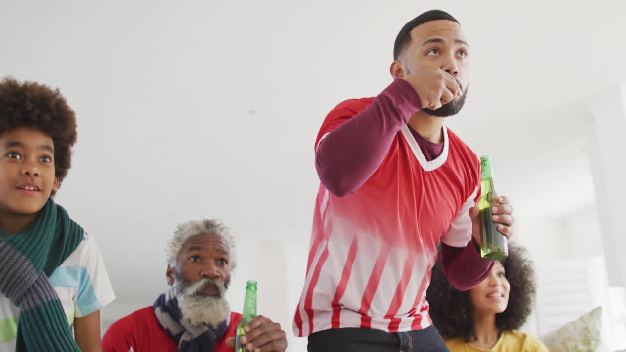 집에서 tv에서 스포츠를 시청하는 동안 다세대 가족이 응원합니다.