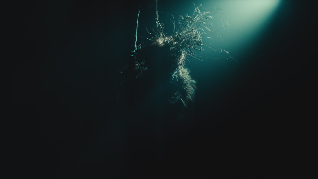 A creepy witch stands in the moody pose during the night storm