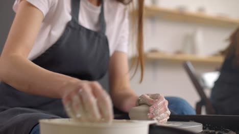 mujer joven en el estudio de cerámica usando rueda de cerámica, cerámica hecha a mano, creativa. primer plano de manos, cámara lenta