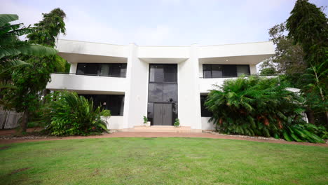 grand white elegant sleek home house wide with black windows and private balcony patios and tropical lawn