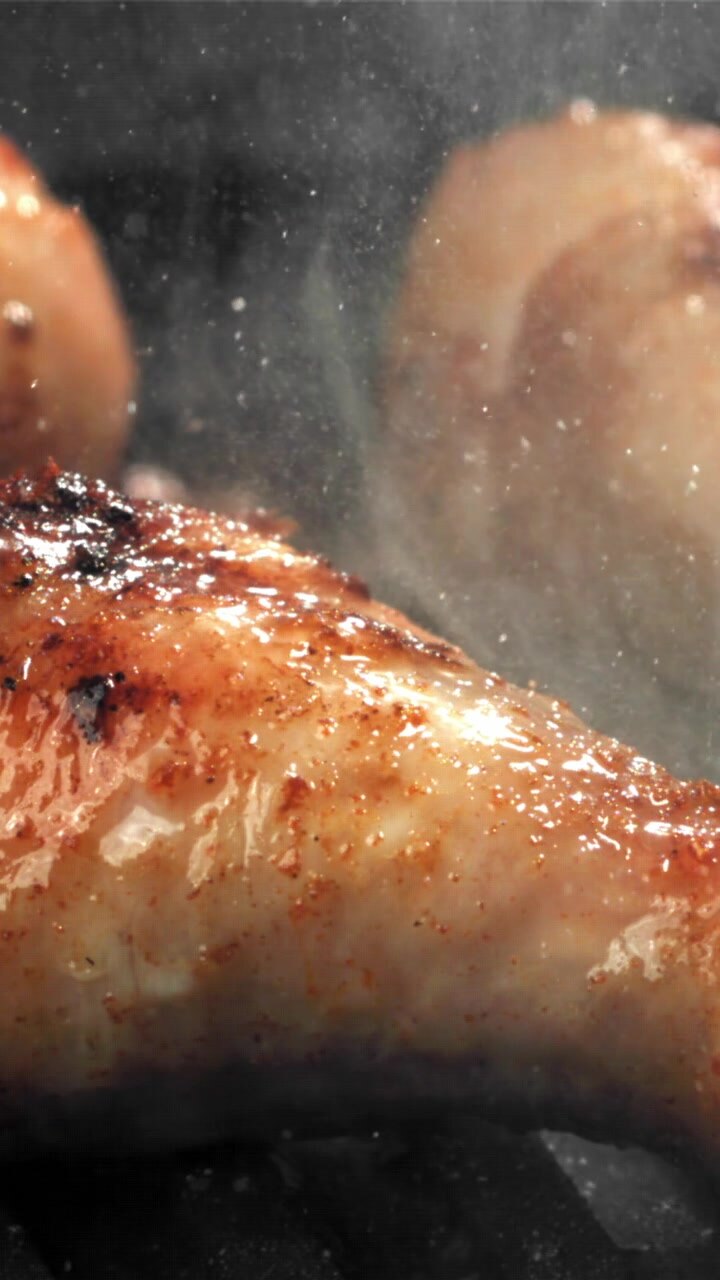 Pollo dorato che sfrigola su una padella calda