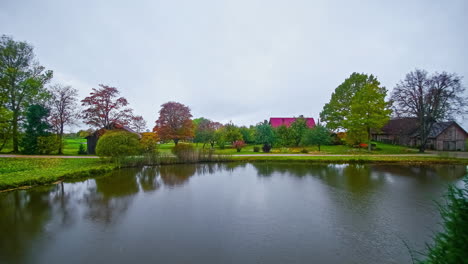 Toma-De-Tiempo-De-Cabañas-Al-Lado-Del-Lago-Durante-Todo-El-Día-Nublado-Durante-El-Día-De-Otoño