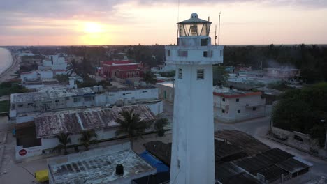 Toma-Aérea-De-Camiones-A-La-Derecha-Al-Amanecer-Con-El-Cierre-Del-Faro-En-Telchac-Puerto-En-Yucatán,-México