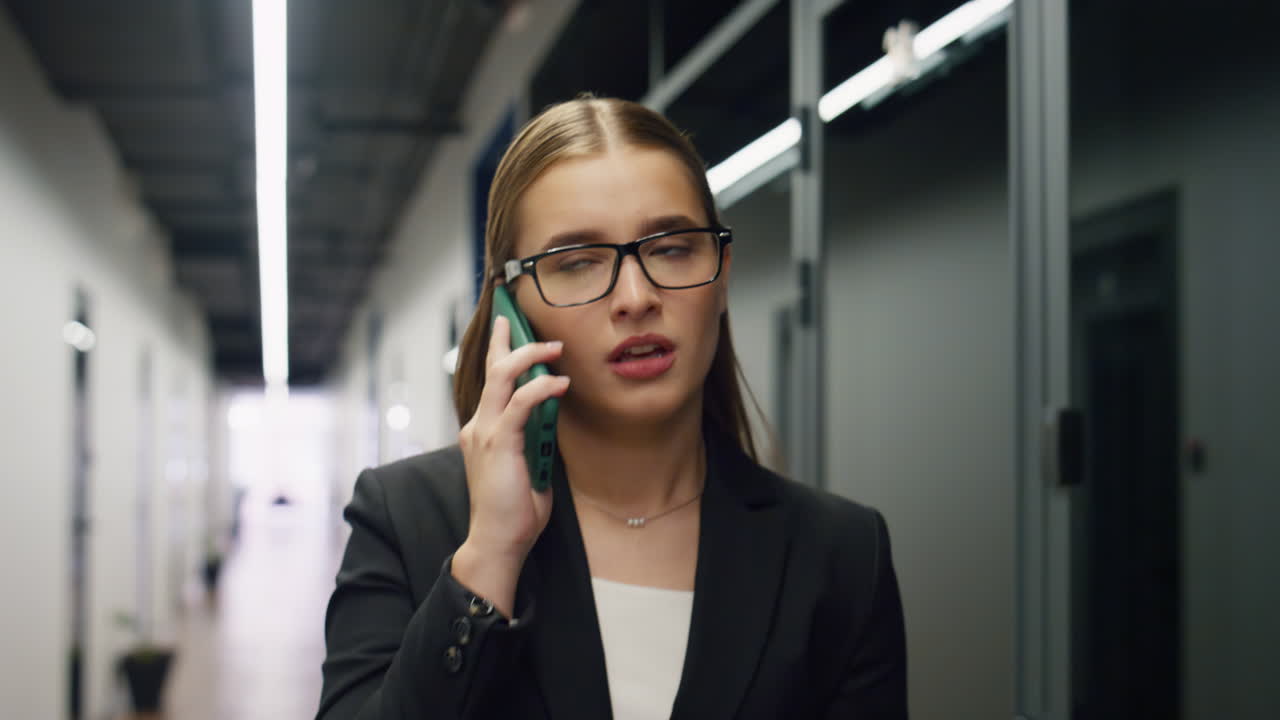 Ritratto di responsabile d'ufficio che parla al telefono camminando in un moderno centro direzionale.