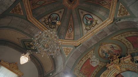painted church ceiling with biblical art and crystal chandeliers in intricate baroque style