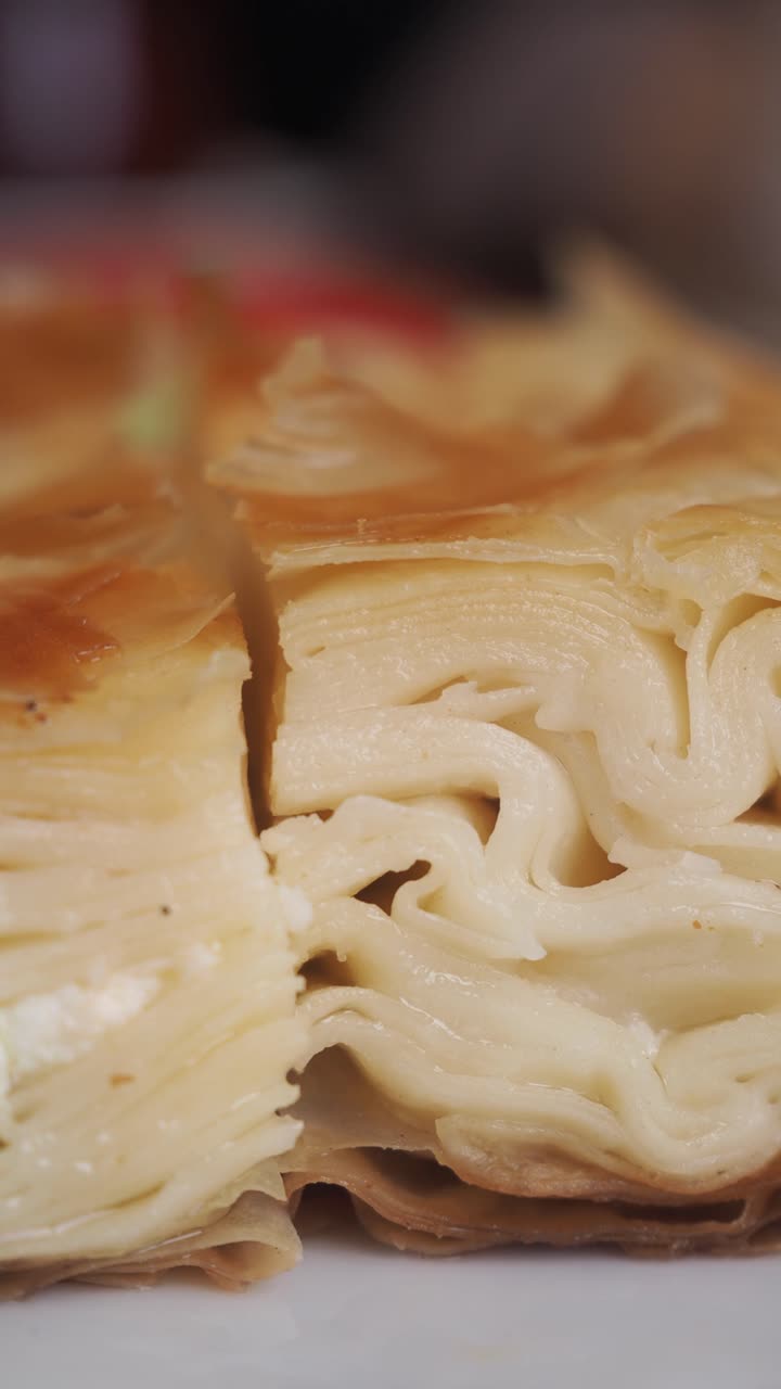 Primo piano di una deliziosa pasta sfoglia al formaggio a strati che viene tagliata.