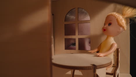 Girl-with-fever-peeks-into-window-of-handmade-dollhouse