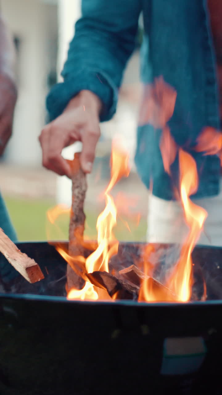Close-up de mãos atiçando o fogo em uma churrasqueira
