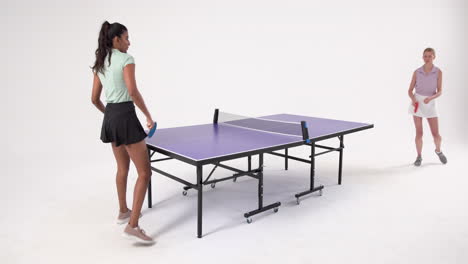 playing table tennis, woman holding paddle and standing next to table