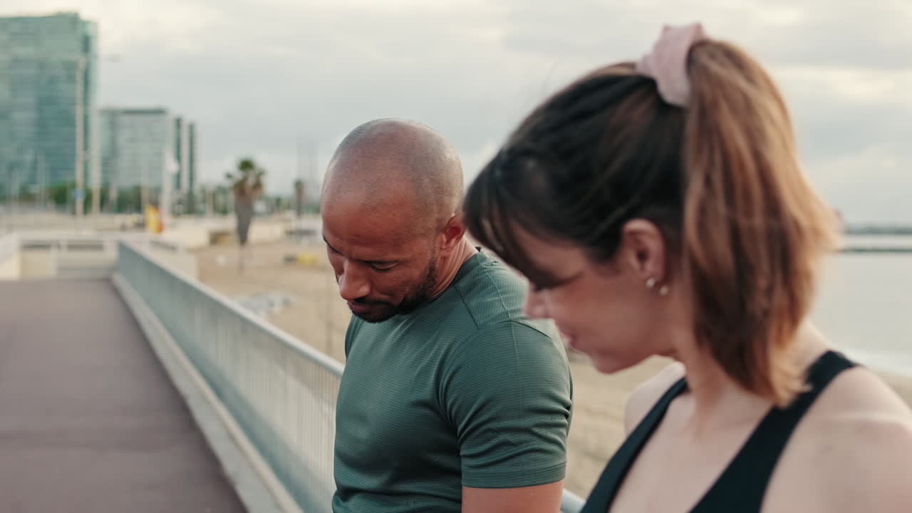 Athletic Couple Stretching Necks on Beach Promenade
