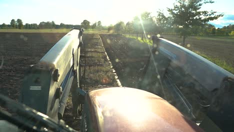 Pov-Durch-Die-Windschutzscheibe-Einer-Landwirtschaftlichen-Traktorkabine,-Die-An-Einem-Sonnigen-Tag-Das-Feld-Pflügt