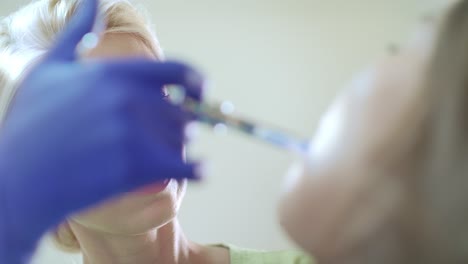 dentista haciendo una inyección de anestesia en la boca del paciente.