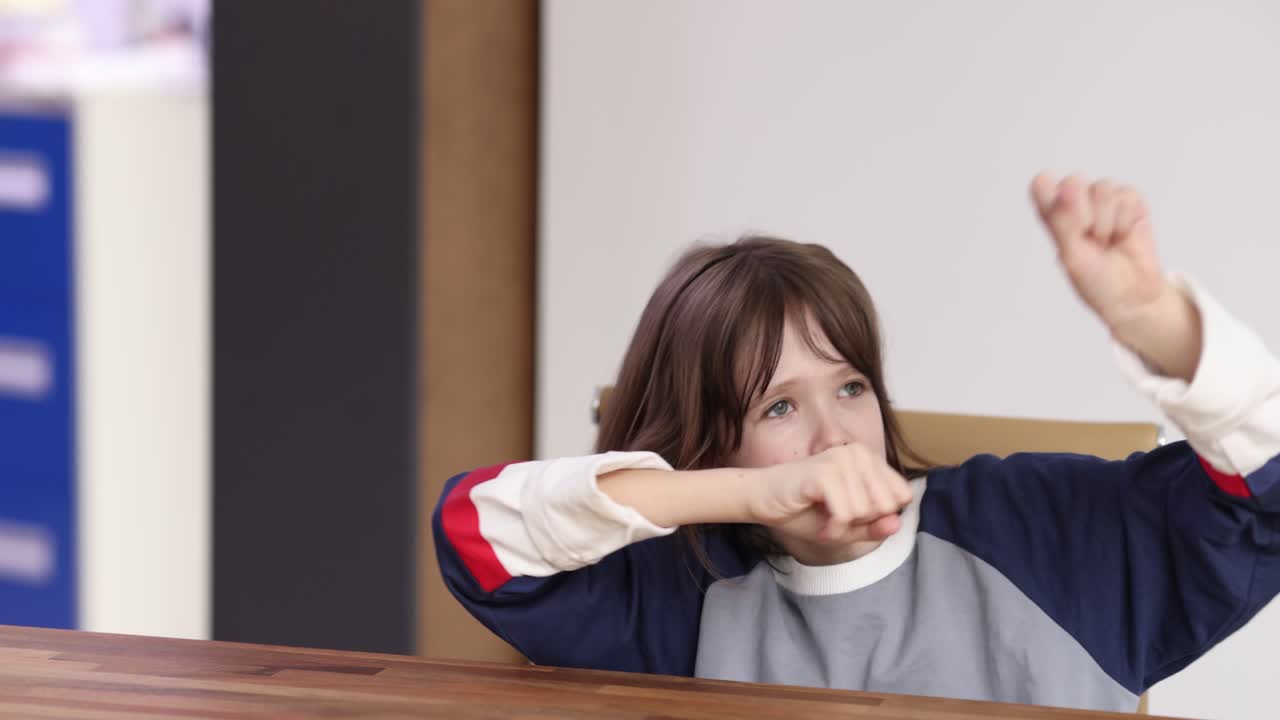 Girl raising her arms at a wooden table