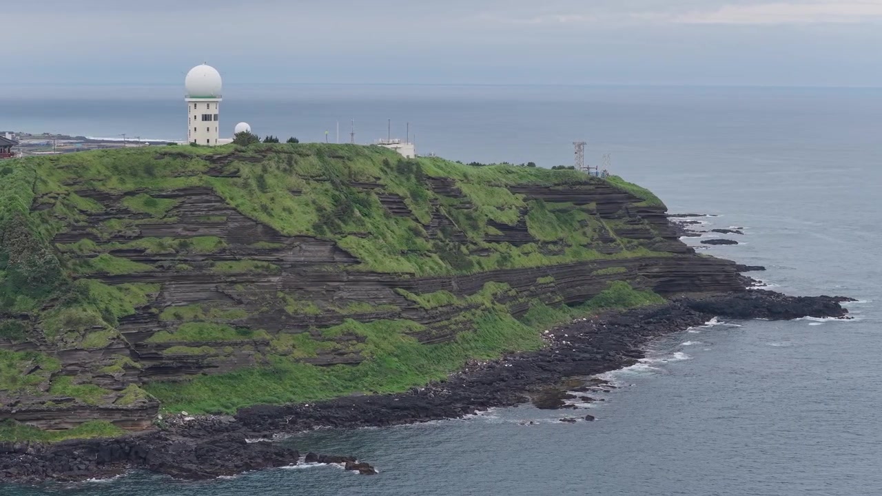 Horizontal aerial view of Eongal Coastal Trail and Chagwido on Jeju Island, South Korea, with the camera halfway orbiting around the volcanic cliffs and coastline