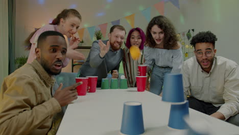 friends playing a cup stacking game at a party