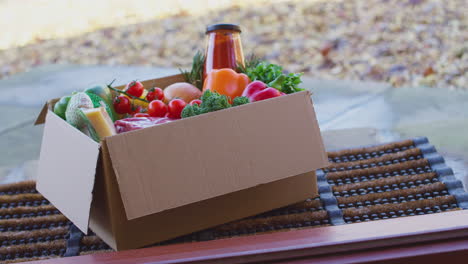 Box-of-fresh-ingredients-for-online-meal-recipe-kit-delivered-to-home-on-doorstep---shot-in-slow-motion