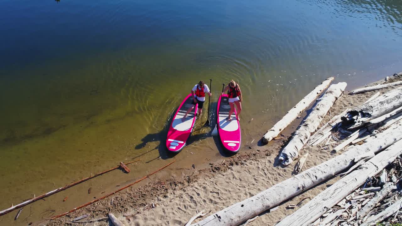 Coppia che ormeggia la tavola da paddle sulla riva del fiume in una giornata di sole 4k