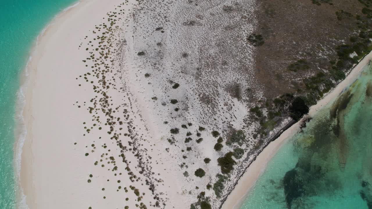 Aerial bird's eye view hyperlapse of ocean waves crashing on island in cayo de agua los roques beach