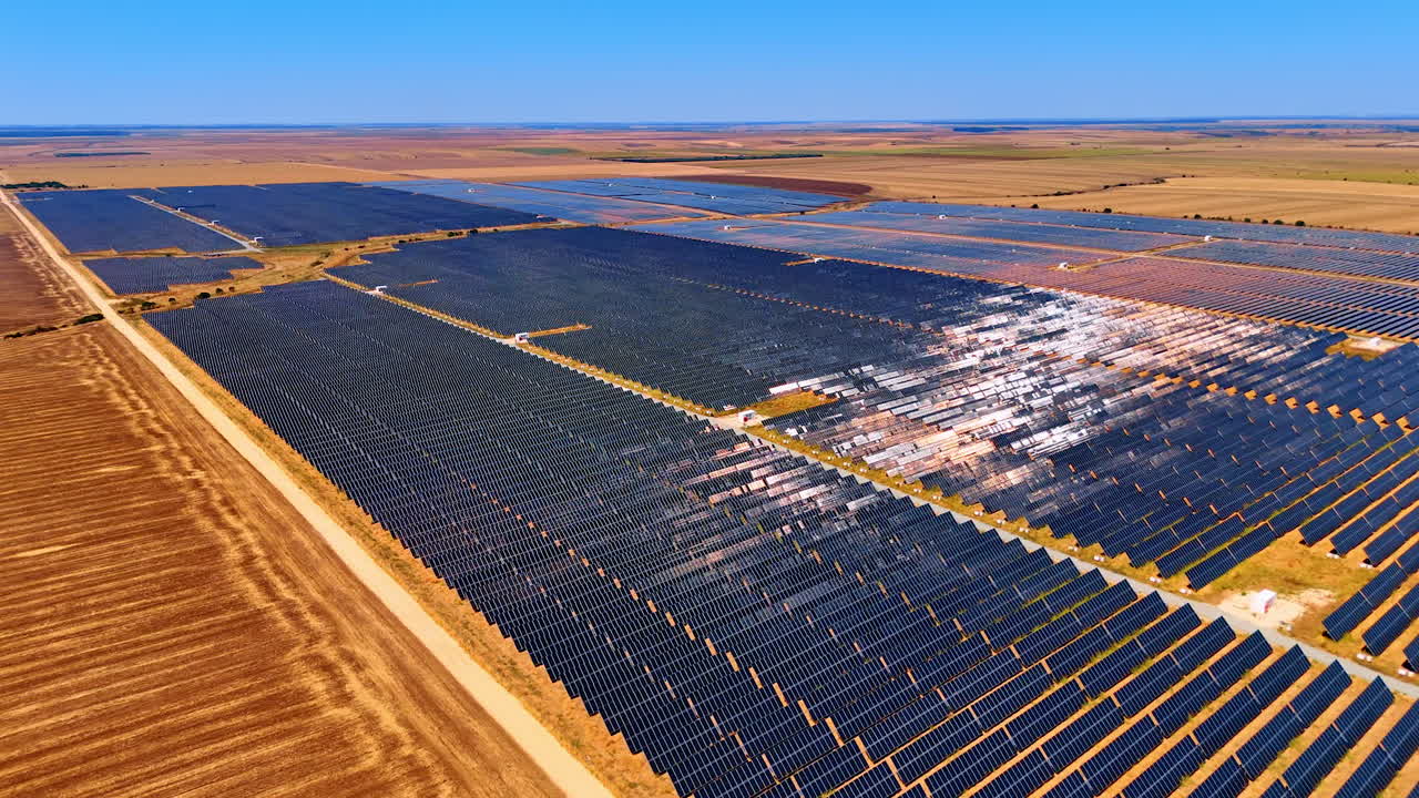 Vast solar farm in open landscape. Solar panels stretch across a wide field under a clear blue sky, showcasing renewable energy in a rural setting