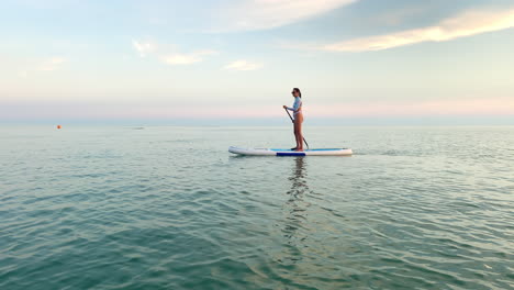 woman paddleboarding at sunset