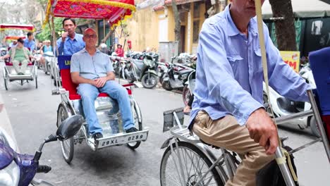 tourists enjoy cyclo ride in busy hanoi