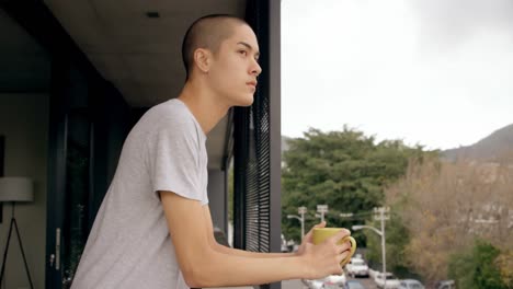 Man-holding-coffee-cup-while-standing-in-balcony-4k