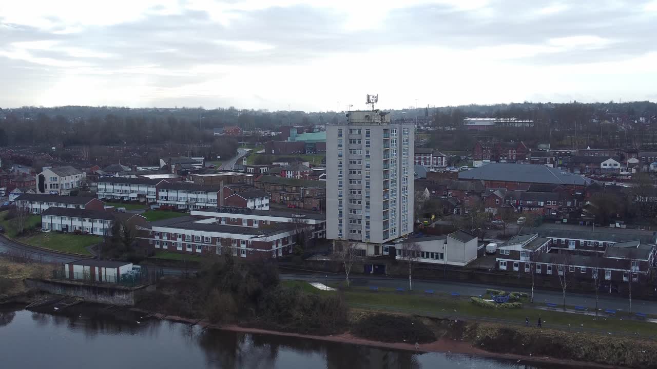 Aerial above regeneration waterfront apartment highrise block in rural old town landscape orbit right