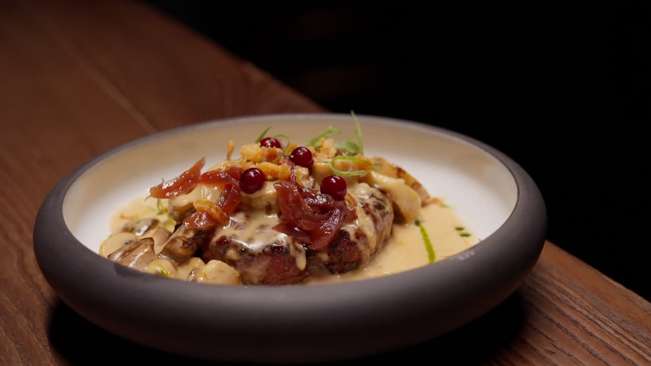 Squisito piatto di carne impiattato con salsa cremosa e frutti di bosco