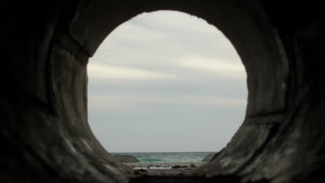 view of the beach and ocean seen from the inside of culvert