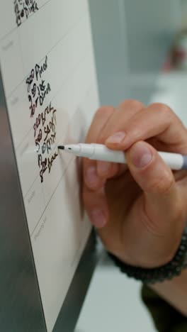 hand writing a shopping list on a magnetic board