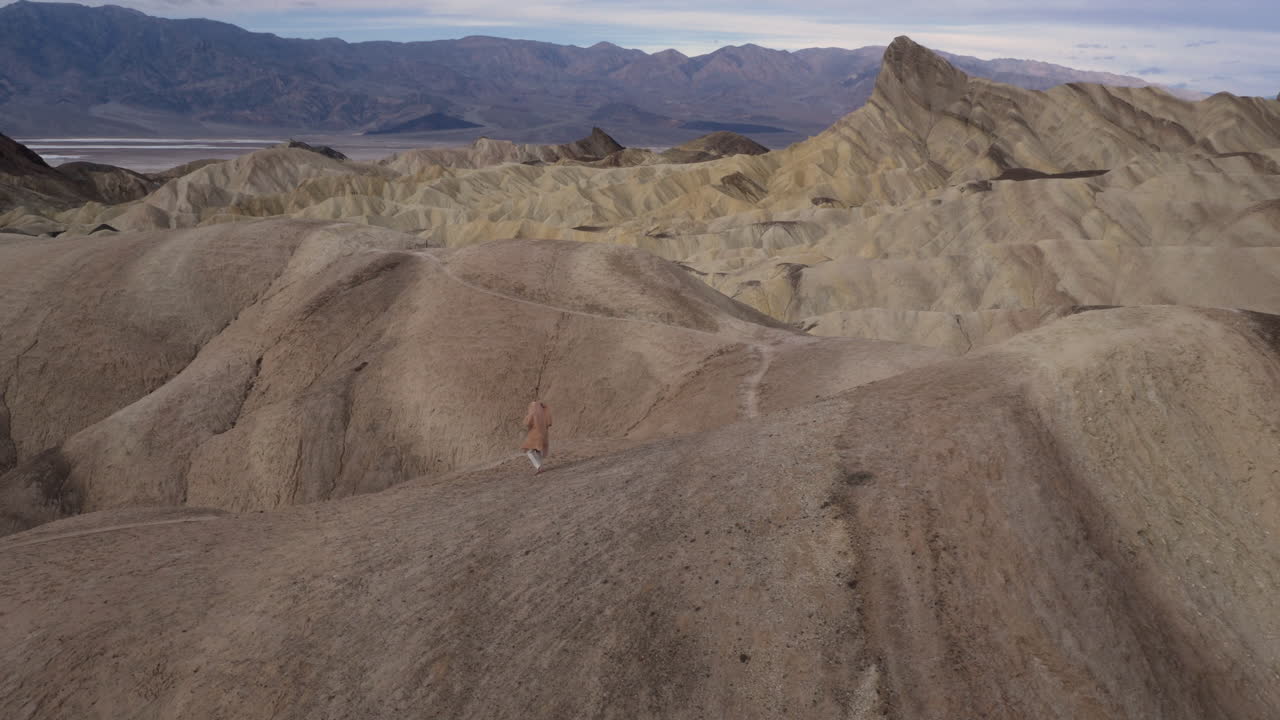 Two people walking through the vast, arid badlands of Death Valley