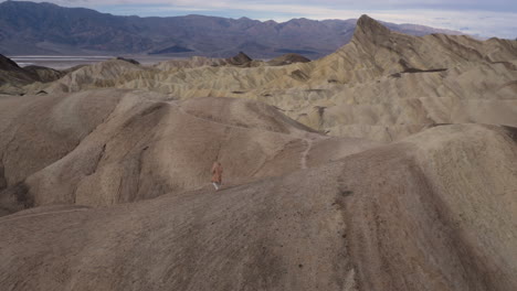 two people walking through the vast, arid badlands of death valley