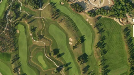 aerial overhead shot of a golf course with beautiful abstract patterns, sand traps, trees and lakes