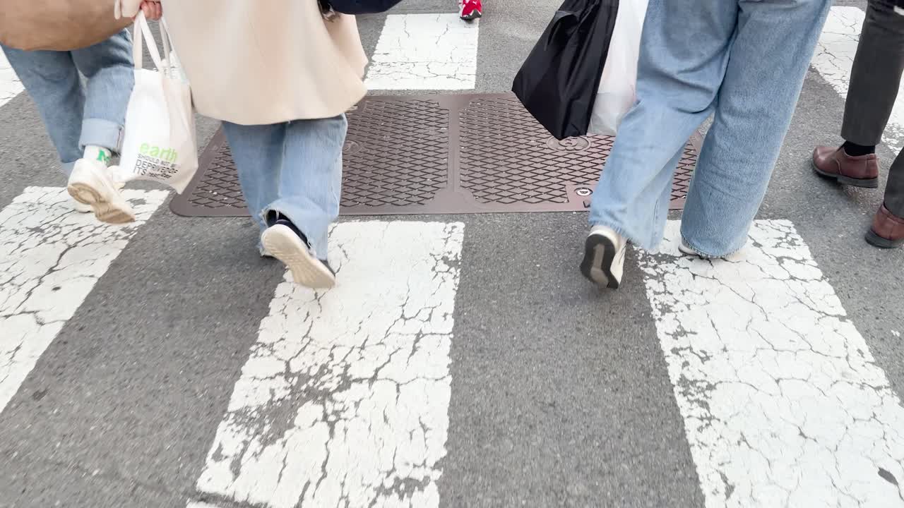 市街地の通りで、人々が横断歩道を渡る様子をローアングルで撮影。
