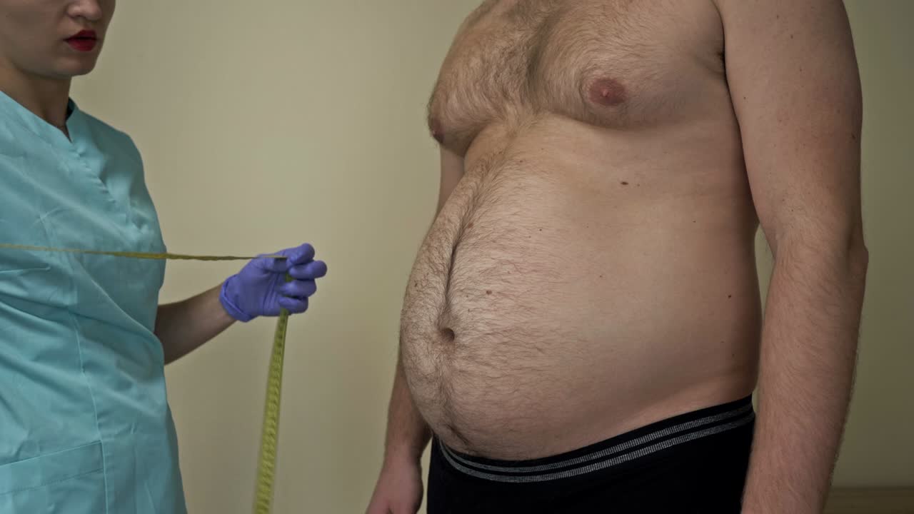 el médico mide la circunferencia abdominal de un paciente con sobrepeso. el propio hombre está insatisfecho con su apariencia