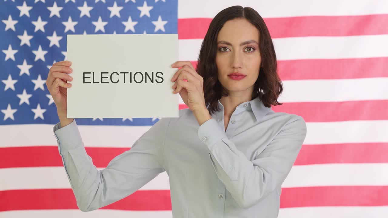 Woman holds elections sign on cardboard in front of american flag