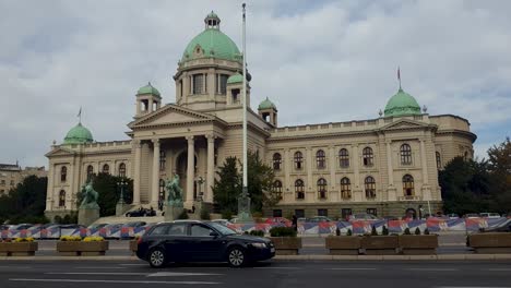 revealing shot of the city assembly of belgrade serbia with car traffic and pedestrians passing in the front on an overcast day