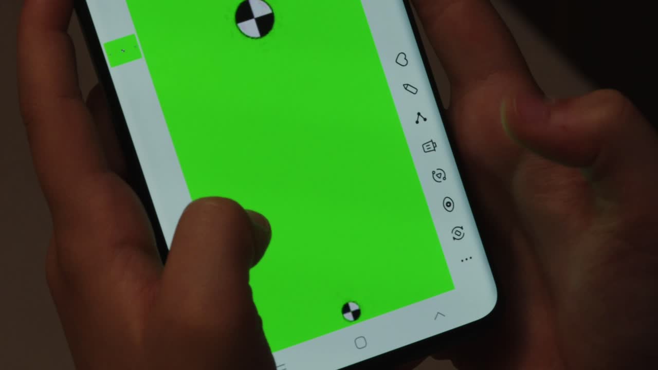 Close up of hands using a smartphone with a bright green screen