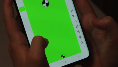 close up of hands using a smartphone with a bright green screen