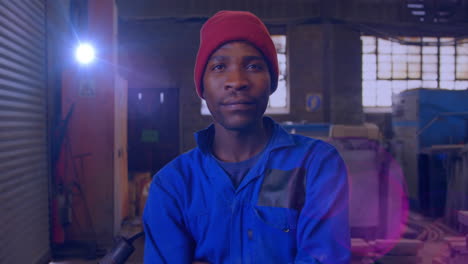 animation of glowing light over african american man working in workshop