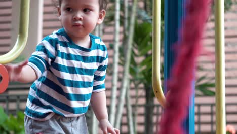 Artistic-shot-of-frayed-play-rope-bridge-at-playground-with-children-playing-out-of-focus-in-the-background