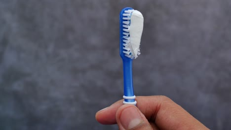 close-up of a hand holding a toothbrush with toothpaste