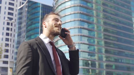 Happy-businessman-talking-on-the-phone-in-the-city-center.