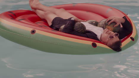 man relaxing on a watermelon float in a pool